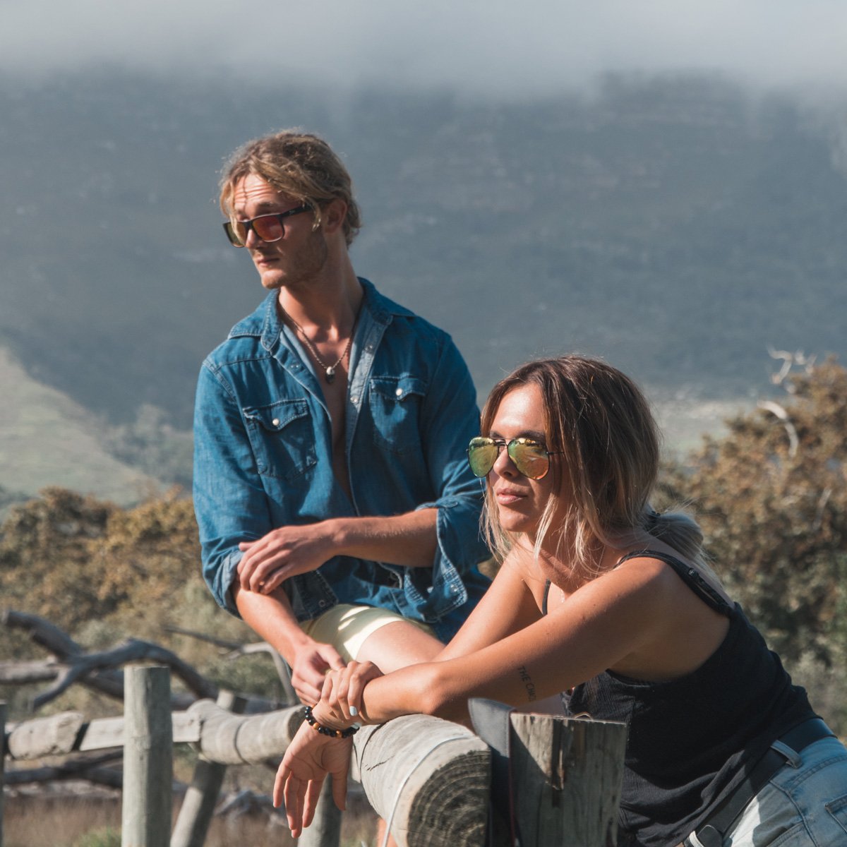 Man wearing mirrored goggles and gray beanie, holding skis in a snowy setting.